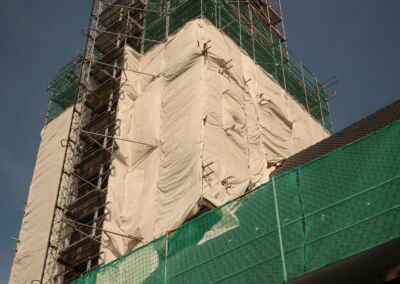 Das Foto zeigt die eingerüstete und teilweise verhüllte Kirche St. Ludgerus in Digden - derTurm besteht aus dem gleichen Drachenfels-Trachyt wie in Mettmann - im August 2019