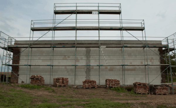 Das Bild zeigt die Scheunengiebelwand mit Gerüst in der Wiederaufbauphase.