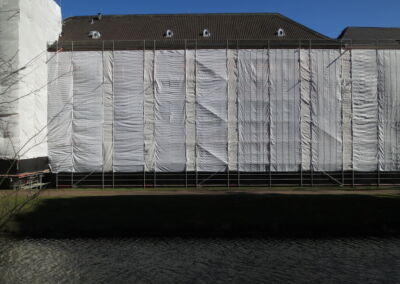 Das Foto zeigt den eingerüsteten und mit Planen verhüllten Haupttrakt von Schloss Kalkum im März 2018