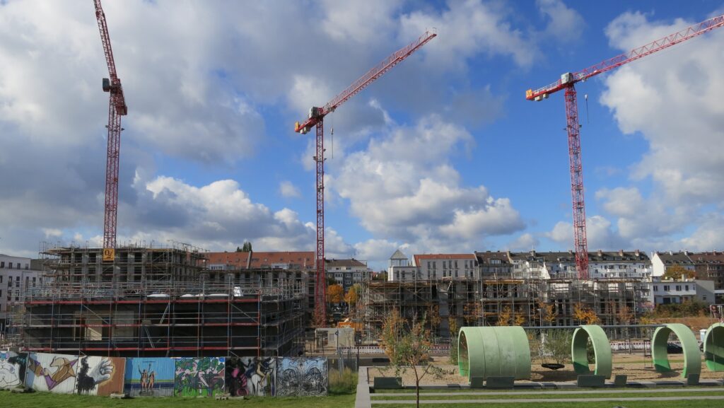 Das Foto zeigt eingerüstete Häuser im Bau, begleitet von drei sehr hohen Baukränen, auf dem Gelände des ehemaligen Güterbahnhofs Düsseldof